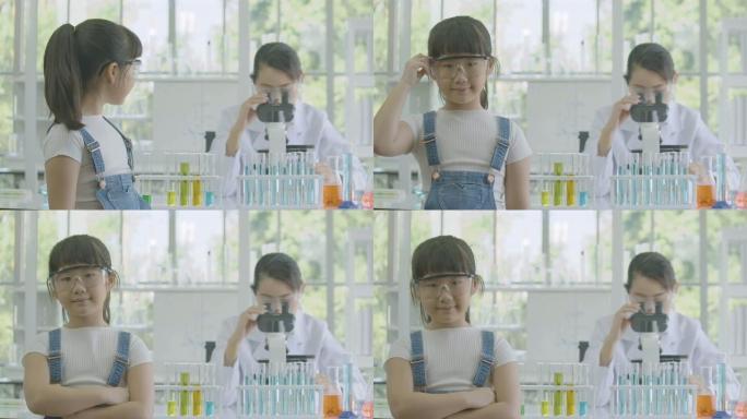 在化学实验室里，一个亚洲小女孩微笑着对着镜头的肖像，背景是女科学家。