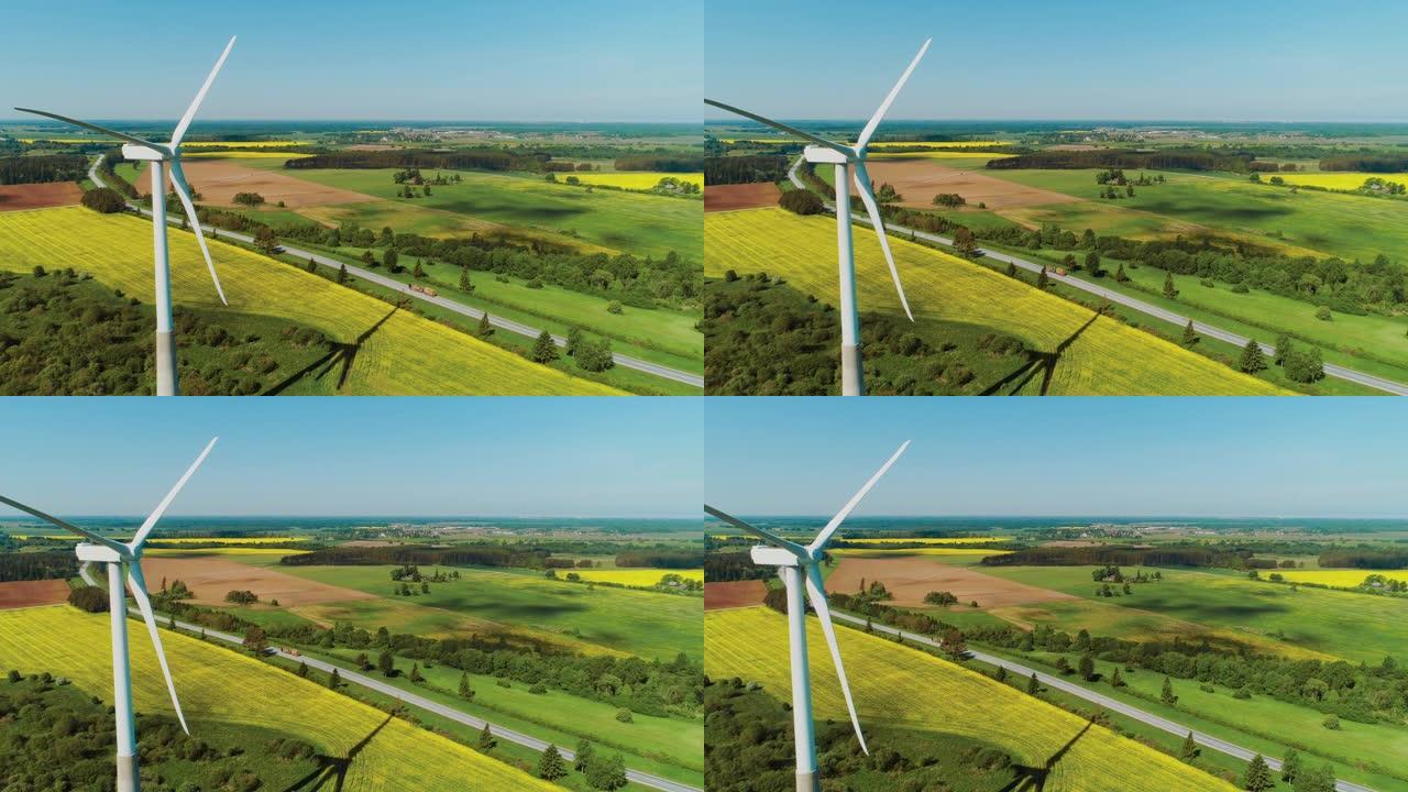 在绿色森林和田野的农村地区，风力涡轮机的空中无人机镜头。风车生产清洁的可再生能源。农村小房子的背景。