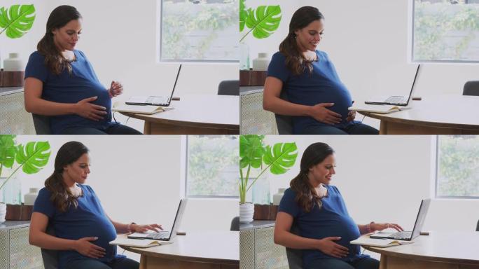 孕妇在家工作时在餐桌上使用笔记本电脑