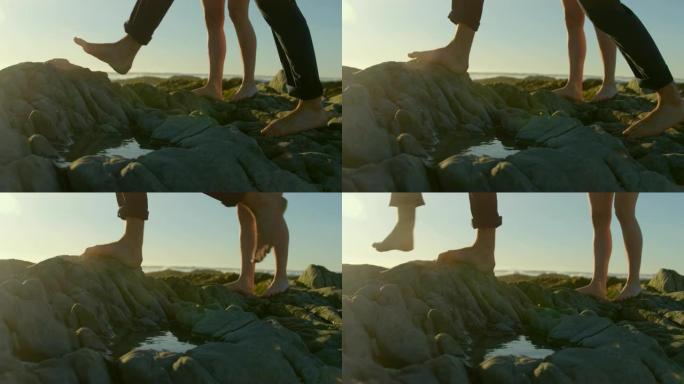 在海滩4k的岩石上行走的夫妇的低矮部分