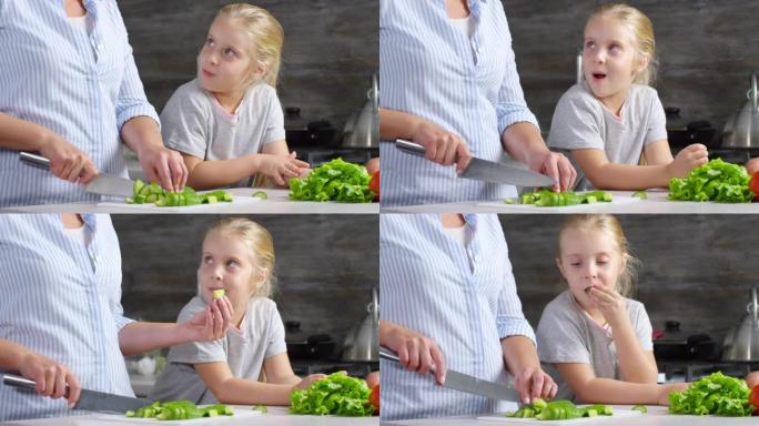 妈妈做沙拉时吃黄瓜的可爱小女孩