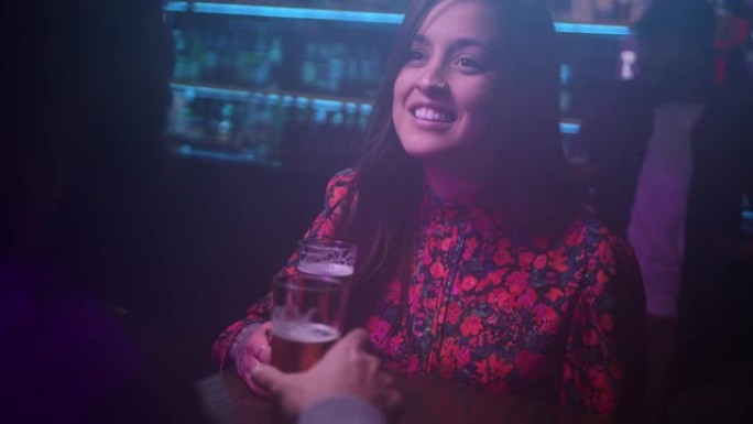 年轻迷人的西班牙裔妇女在时尚酒吧里喝啤酒