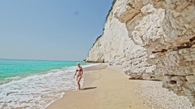 年轻女子女士在意大利普利亚阳光明媚的绿松石海中涉水