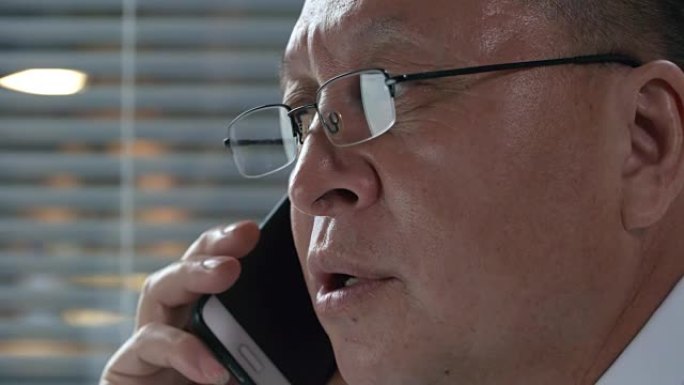 戴眼镜的亚洲男子的特写镜头在电话中交谈