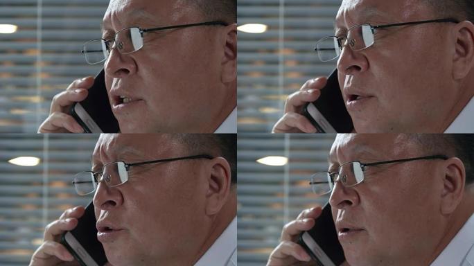戴眼镜的亚洲男子的特写镜头在电话中交谈