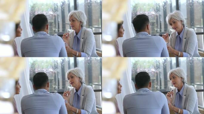 一位高级女士在填写剪贴板应用程序时仔细聆听了她对面的一对年轻夫妇。