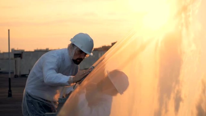一名男性专家正在擦拭太阳能建筑的阳光表面。环保能源概念。