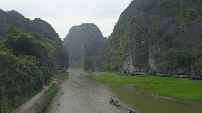 空中: 游客们在河上划着划过石灰岩悬崖的小船。