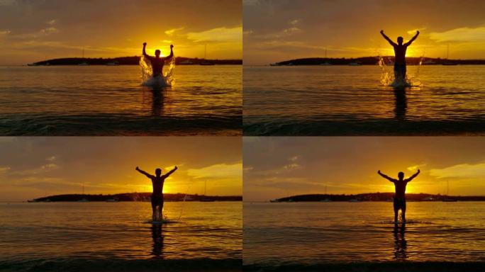 剪影女士旺盛的男子在日落时跳出海洋，克罗地亚佩列萨克