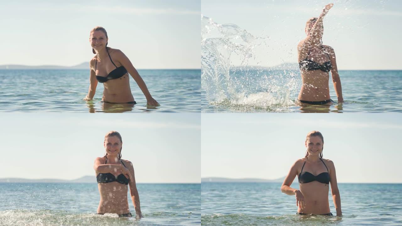 女人在海滩上享受夏天，站在海洋中，在炎热的晴天将海水溅向相机