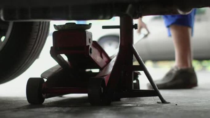 4k: 机械师在汽车维修店使用地板千斤顶汽车。