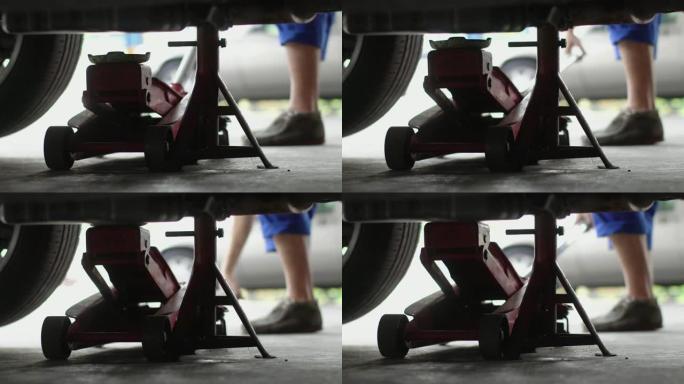 4k: 机械师在汽车维修店使用地板千斤顶汽车。