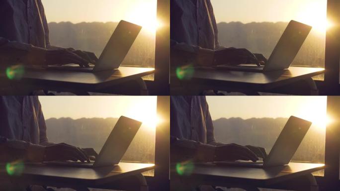 男子在日落窗前使用笔记本电脑