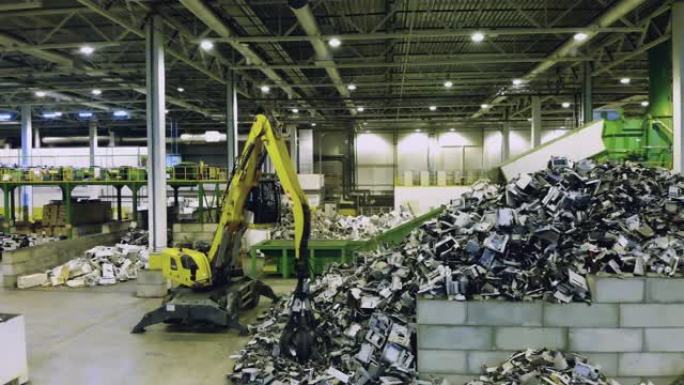 垃圾场单位，有一个装载机抓取和转移垃圾。回收工业概念，塑料垃圾回收工厂。