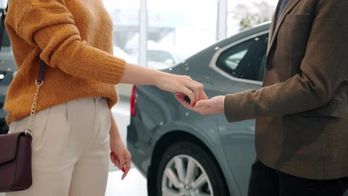 女人从推销员那里拿到车钥匙，然后握手庆祝成功的交易