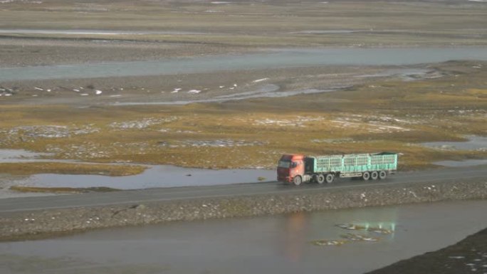 旧货车在穿越风景秀丽的藏族平原的空旷道路上加速行驶。