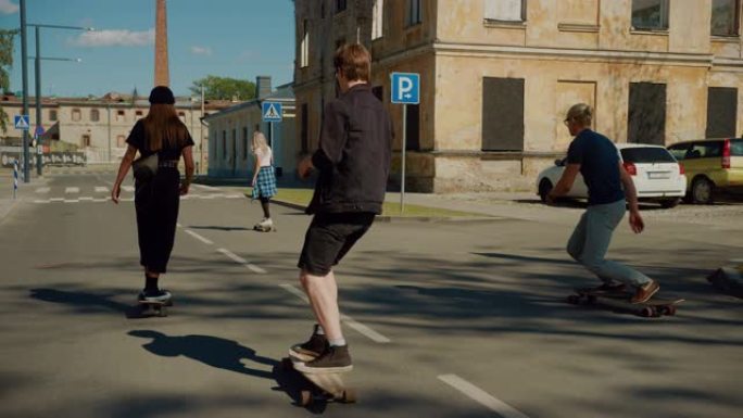 时尚酷的青少年滑冰。两个女孩和两个男孩骑在滑板和长板上，穿过城市文化后工业部分的时髦地区