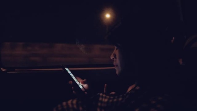 车上的年轻女子晚上用智能手机