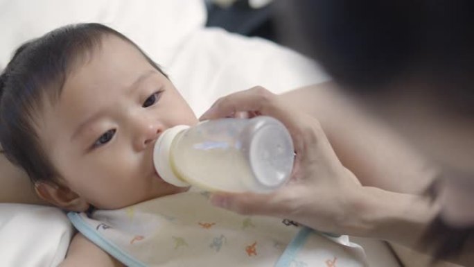 母亲用瓶子里的牛奶喂养亚洲新生女孩