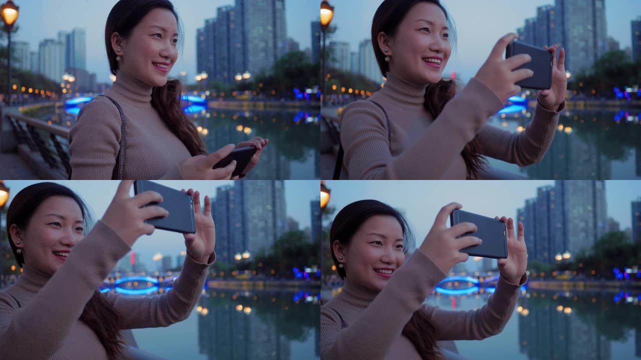 长发亚洲妇女使用电话拍摄城市的照片