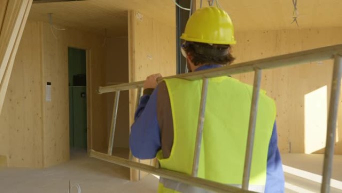 特写: 建筑工人带着工具箱和梯子离开施工现场。