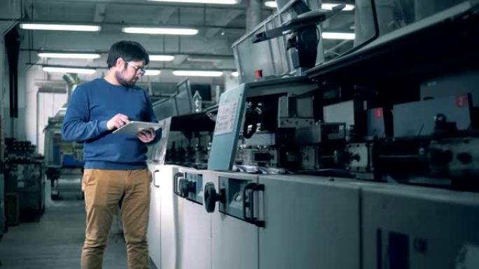 一名男子检查印刷设备工作，关闭。