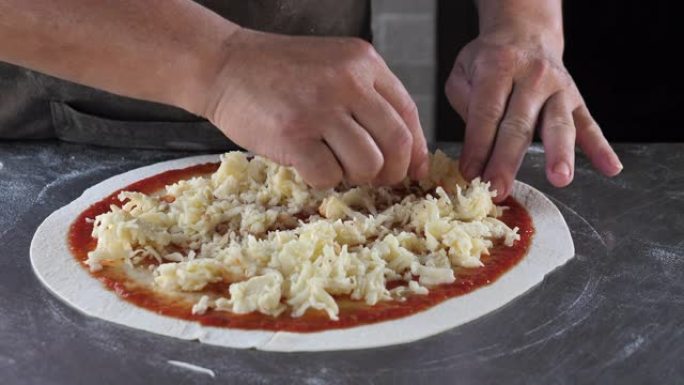 厨师在比萨店准备披萨时将磨碎的奶酪放在面团上做饭