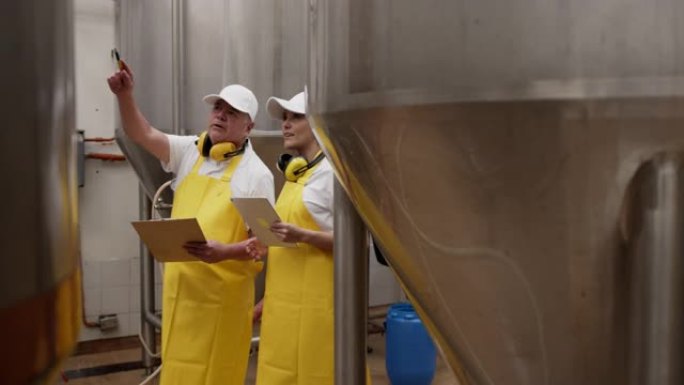 高级主管在啤酒厂拿着平板电脑时向女操作员解释某些事情