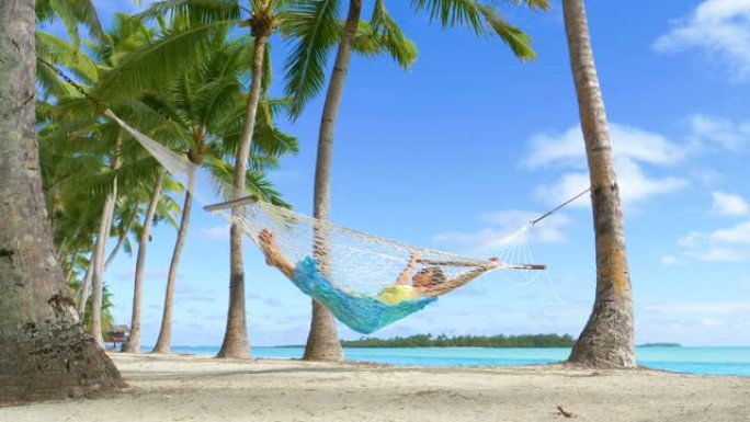低角度: 女性旅行者在吊床上小睡一会儿，在海边放松。