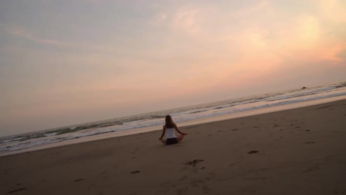 日落时在海滩上冥想的女人