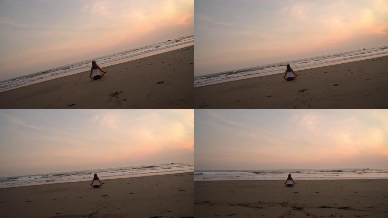 日落时在海滩上冥想的女人