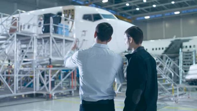 飞机维修技工和总工程师在大型飞机开发设施中进行讨论，咨询蓝图。他们分析、检查、开发和设计飞机