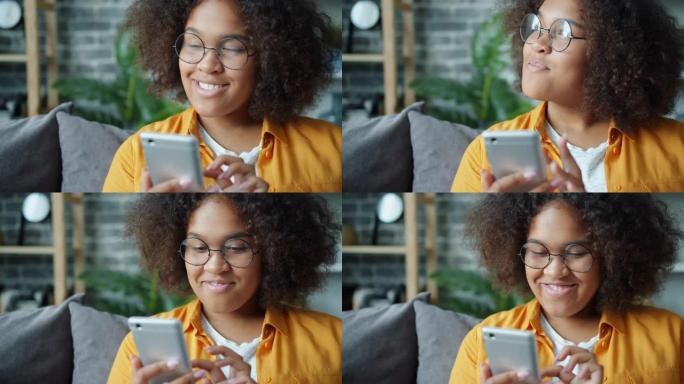 快乐的非洲裔美国少年在家中使用智能手机大笑