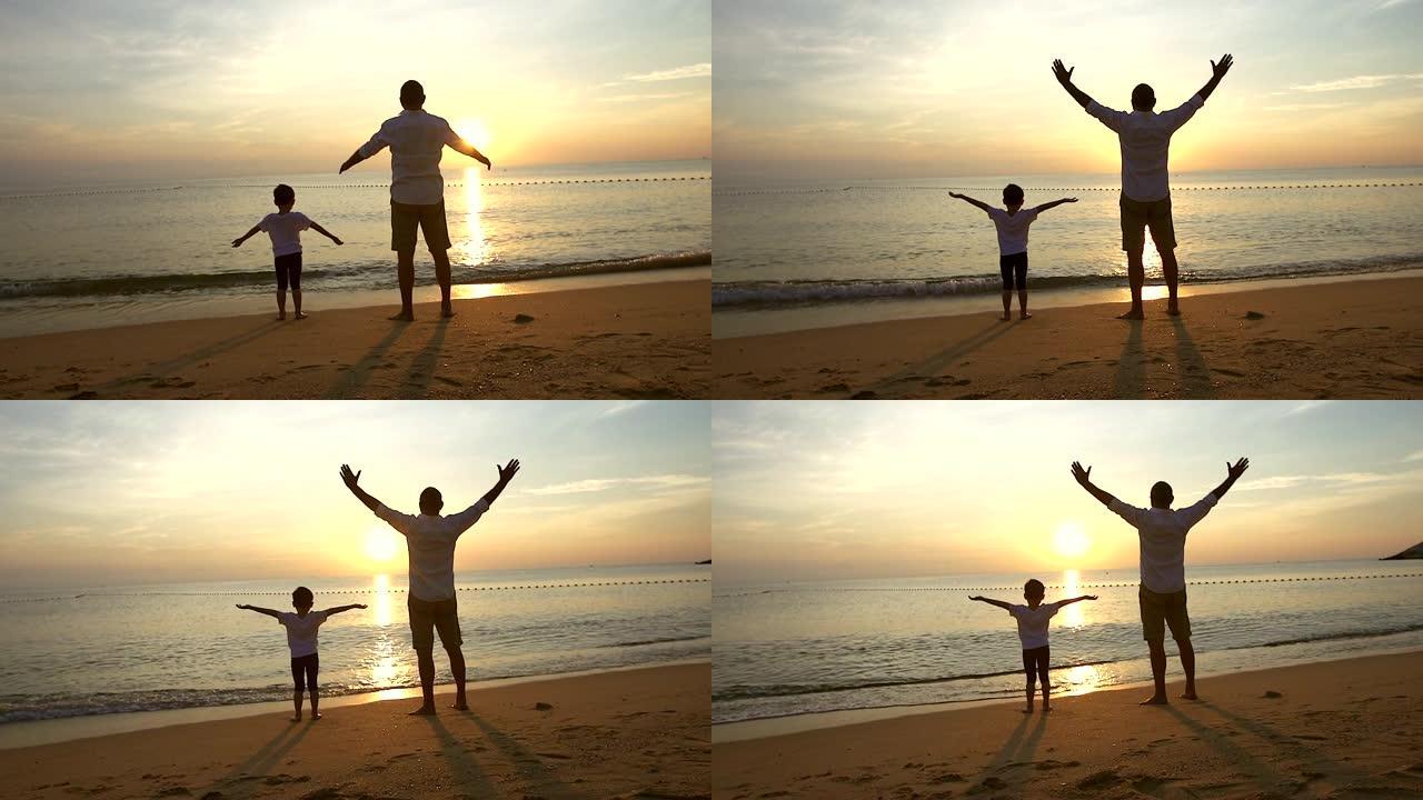 父亲和儿子在日出时站在海滩上，他们一起度过了美好的家庭时光。用慢动作摄像机拍摄。