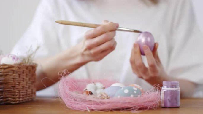 兔子坐在桌子上，女人装饰复活节彩蛋