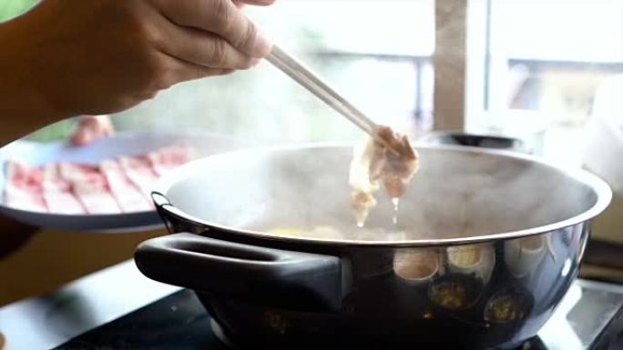 用筷子、沙锅和寿喜烧搅拌的煮汤火锅蘸肉片的4k慢动作镜头日式美食概念