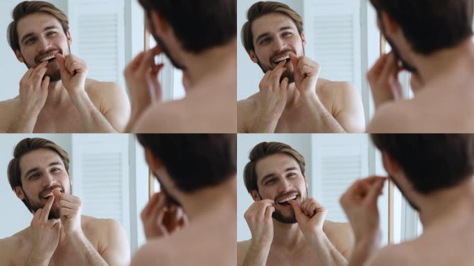 年轻人在镜子里用牙线清洁牙齿