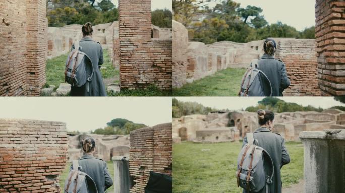 相机跟随年轻的女人背着背包在度假旅行中走在意大利Ostia Antica的古老红砖废墟中。