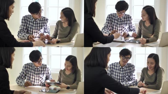 年轻的亚洲夫妇签订合同并购买房屋，房地产经纪人