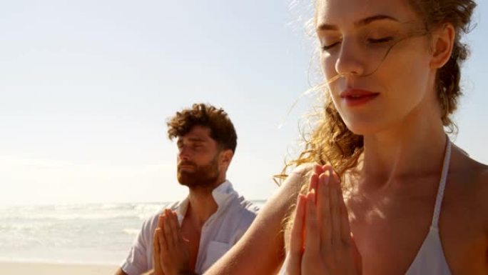 夫妇在阳光明媚的一天在海滩上表演瑜伽4k