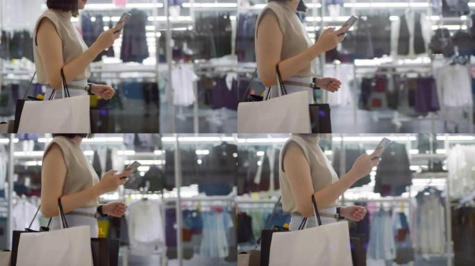 面目全非的女士带着购物袋和智能手机在购物中心散步