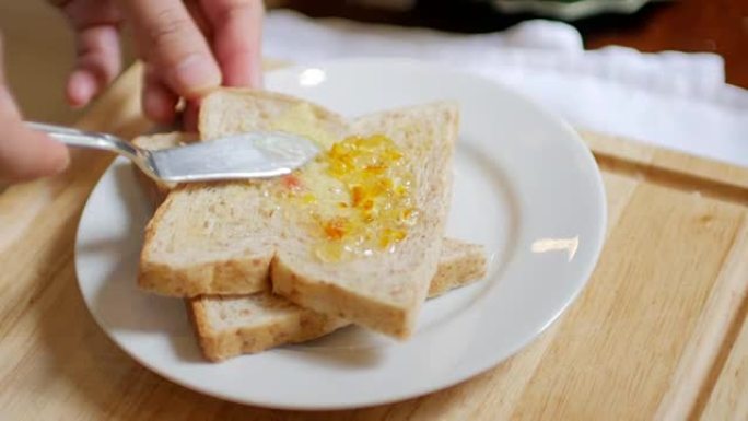 手握面包和果酱做早餐