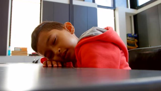 4k学校教室里睡在桌子上的亚洲男生的侧视图