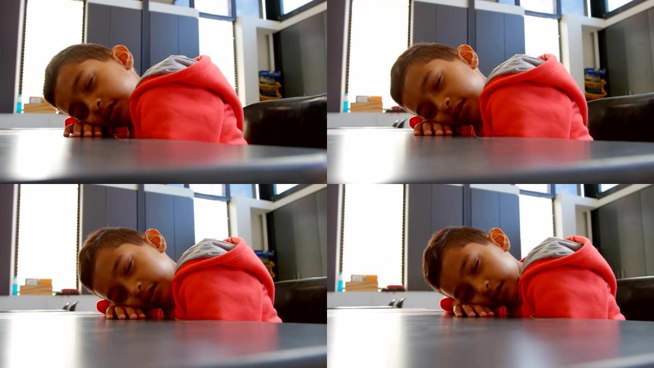 4k学校教室里睡在桌子上的亚洲男生的侧视图