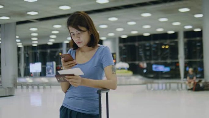 年轻女性站在机场的智能手机上检查战斗。