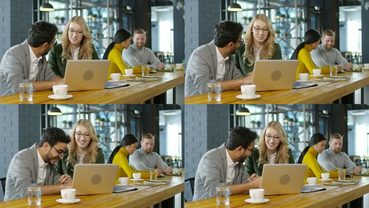 欢乐的同事在咖啡馆里聊天和在笔记本电脑上工作