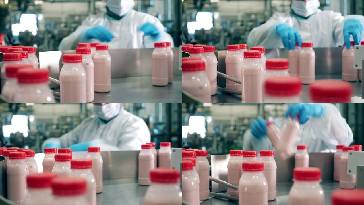 乳品厂的工人从传送带上拿酸奶瓶子。