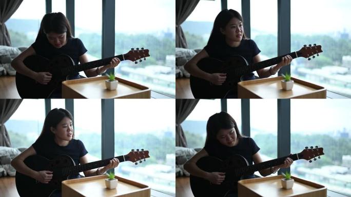 一位亚洲华裔小姐闲暇时在家弹吉他，爱好愉快
