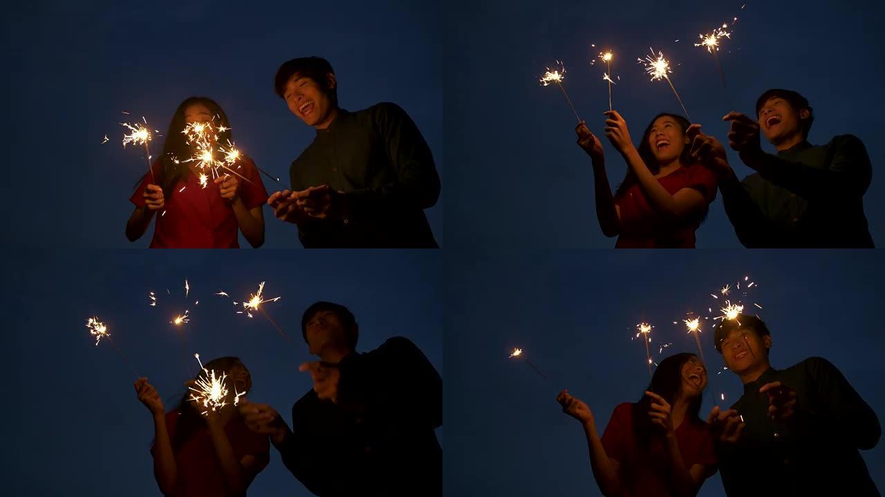 年轻的亚洲夫妇在慢动作的屋顶上一起放烟花。