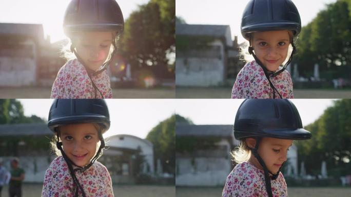 真实的近距离拍摄一个可爱的小女孩与骑师头盔是骑着一匹白马在骑马厩与阳光